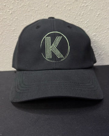 Black cap with a logo on a dark surface and light gray background